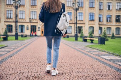 Girl with large bag on her back walking toward a college building